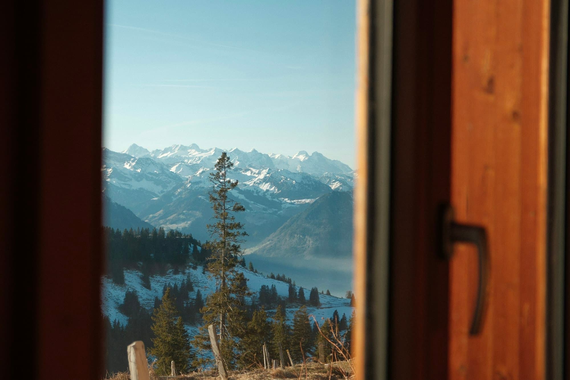 Warm wood-lined interior of a Tribe Inn room opening onto the Sangla valley